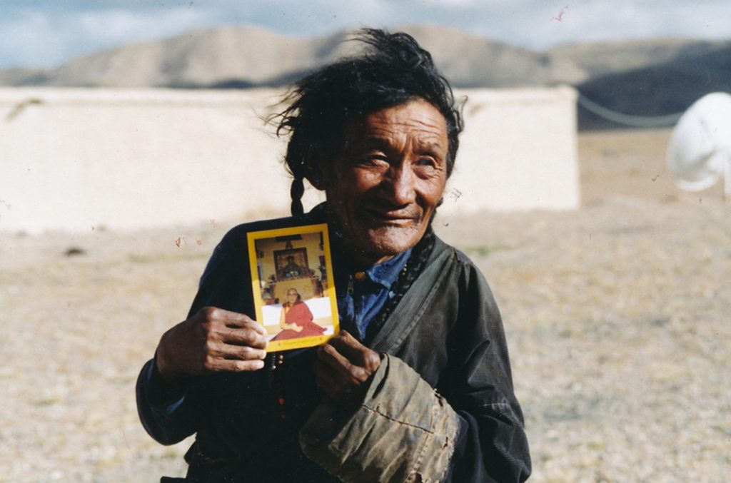 Tibetan man holding photo of the Dalai Lama