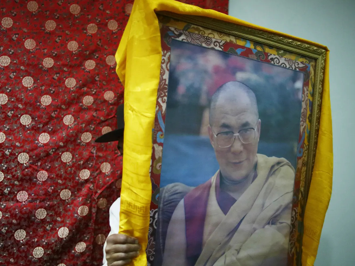 A Tibetan man carries a portrait of Dalai Lama