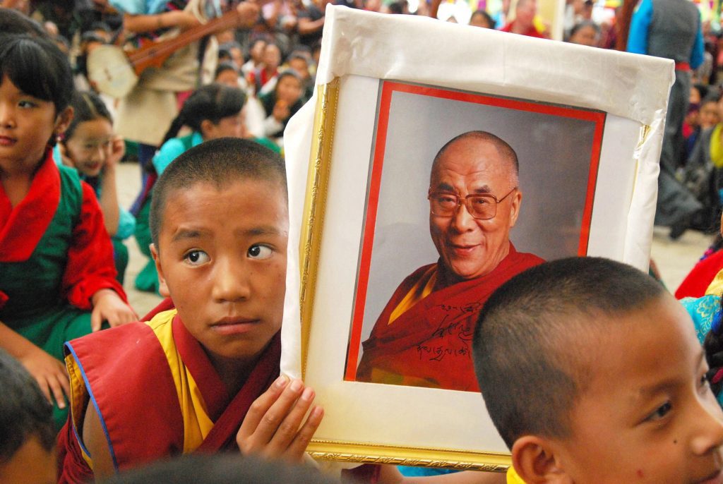 Tibetan boy holding a photo of the Dalai Lama.