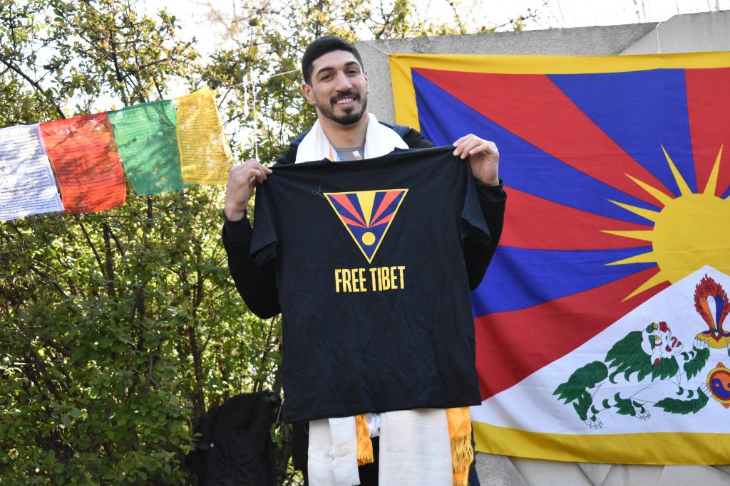 Enes Kanter Freedom holds up a navy blue Free Tibet T-shirt.