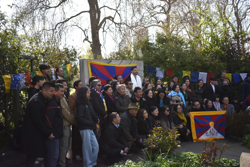 Enes Kanter Freedom and the Tibetan community pose for a photo in front of the Tibetan flag.