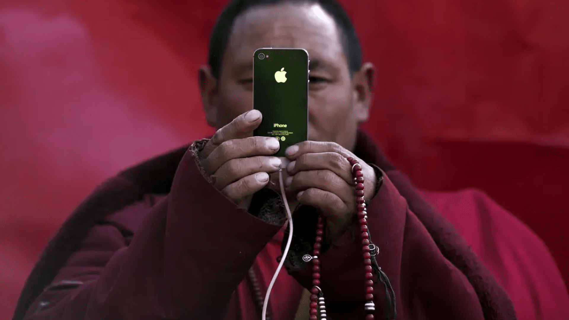 A Tibetan buddhist monk holing up a phone Image from REUTERS/Damir Sagolj