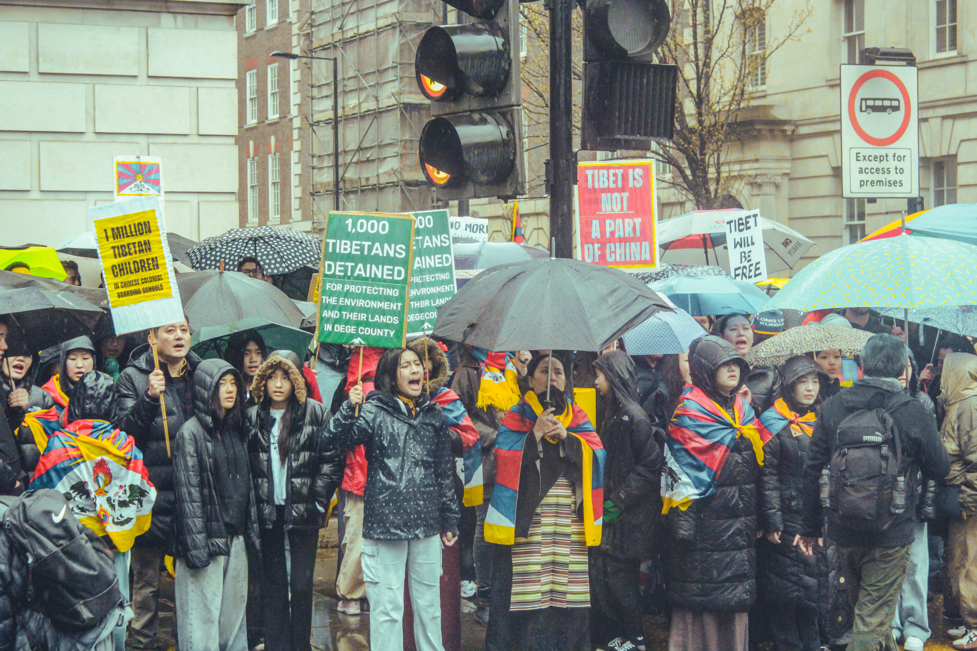 Protesters gather outside of the Chinese Embassy in London, with Tibetan flags draped over their shoulders, chanting slogans.