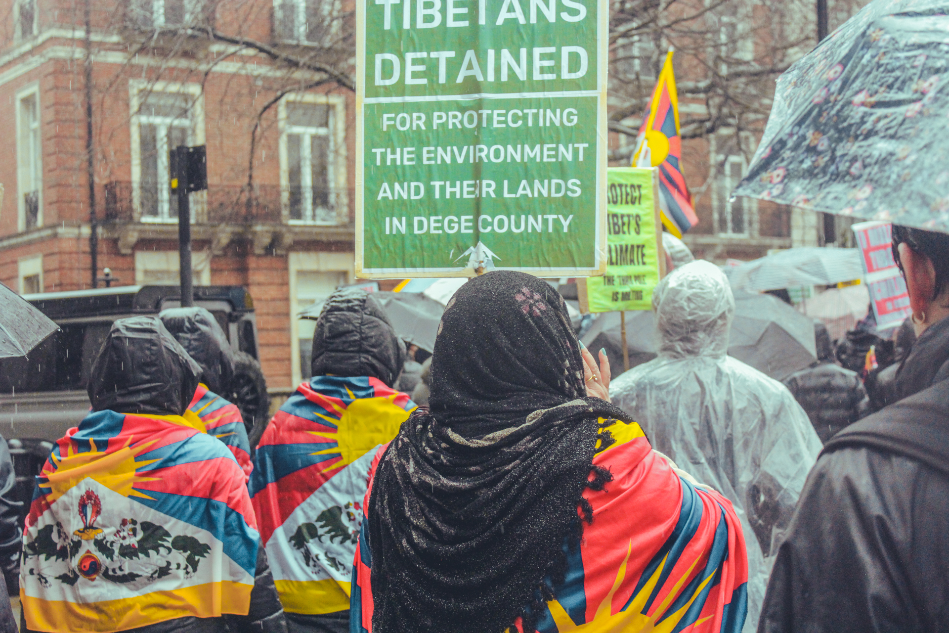 Protesters wear Tibetan flags over their shoulders, holding placards and calling for the freedom of Tibetans detained in Dege County.